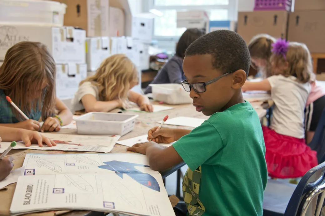 Elementary students focused on their work around a shared classroom table