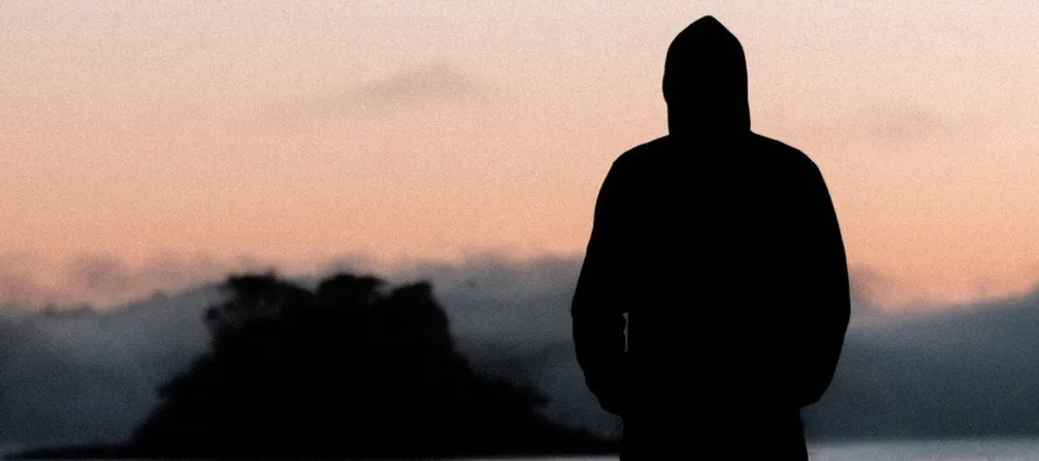 Silhouette of a person in a hooded sweatshirt at dusk