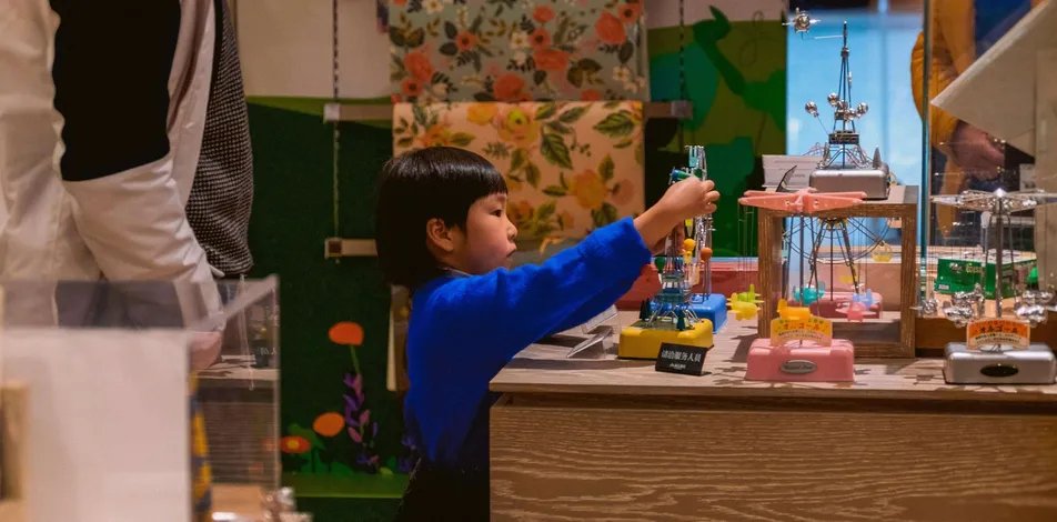 A young student reaches toward a model on a classroom table