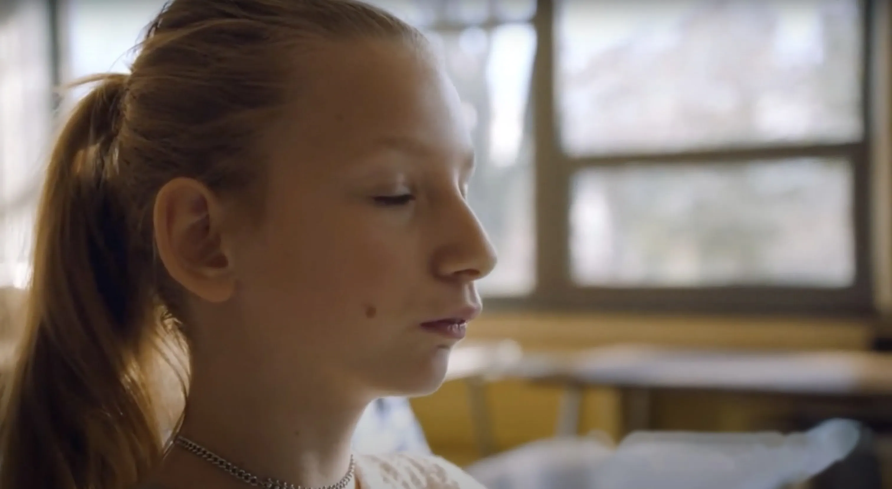 A student sits with eyes closed in a sunlit classroom during a daily mindfulness practice