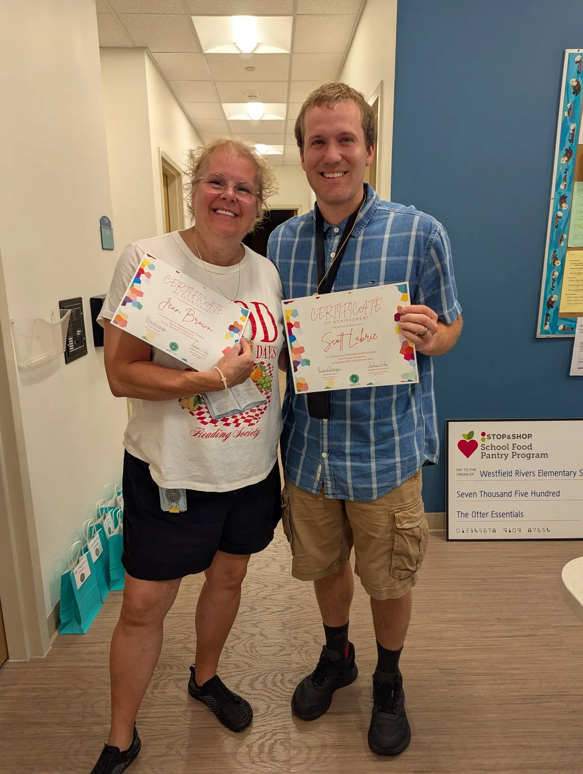 Two teachers smiling and holding Top 10 Inner Explorer certificates