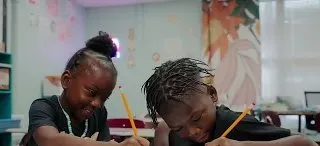 Two young students working side by side at a classroom table