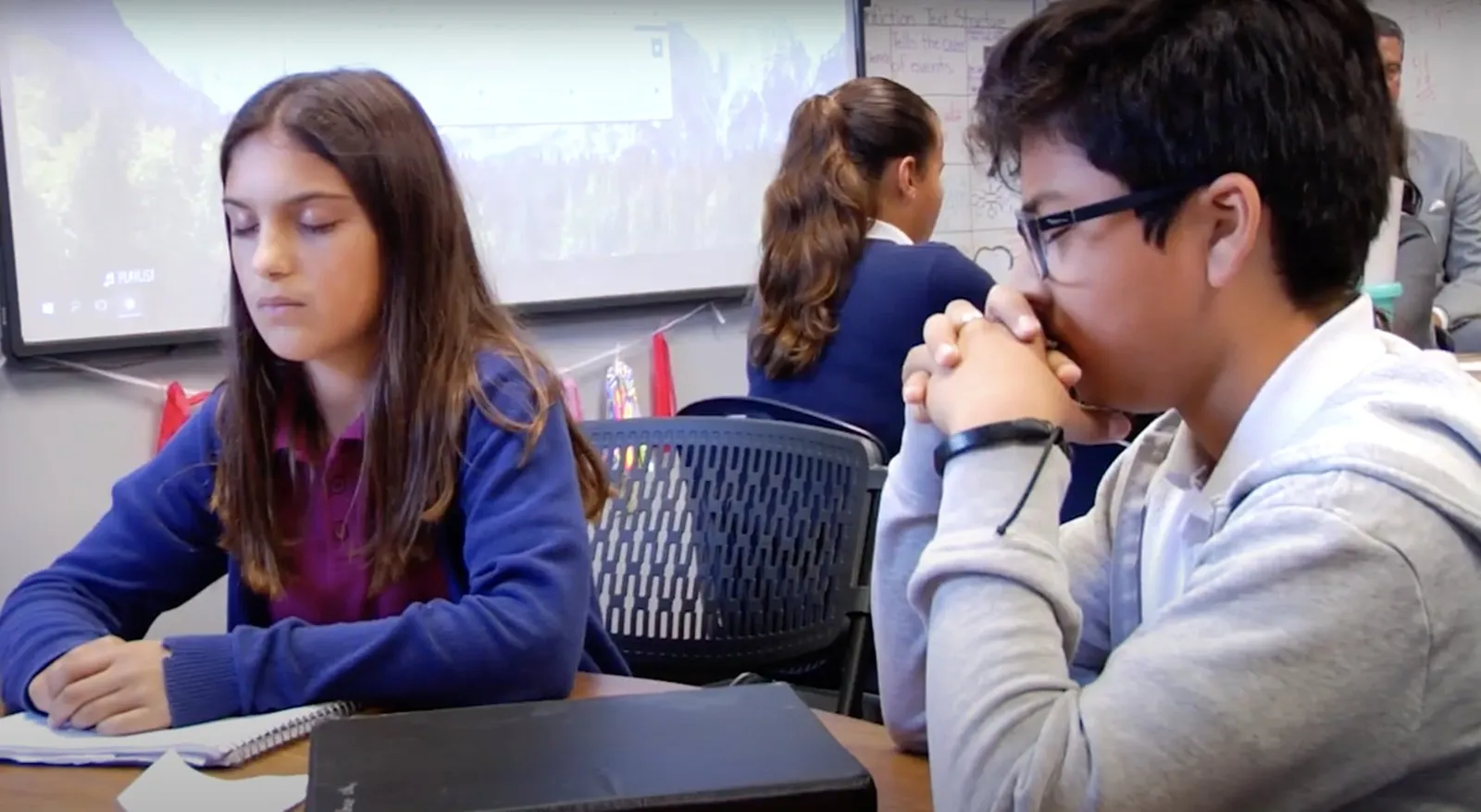 Middle school students practice with eyes closed while a school leader looks on
