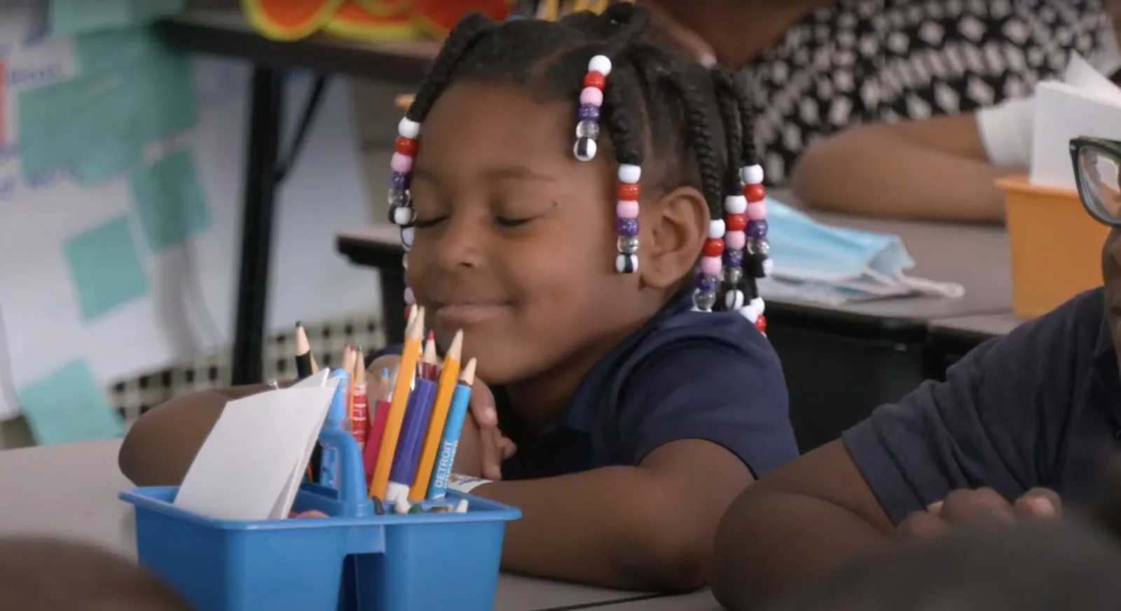 A young student smiles with eyes closed at her desk during a mindfulness practice