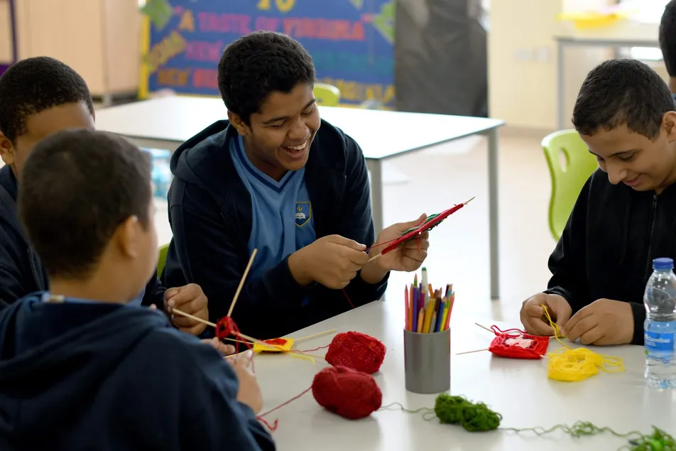 Middle school students knitting together at a classroom table