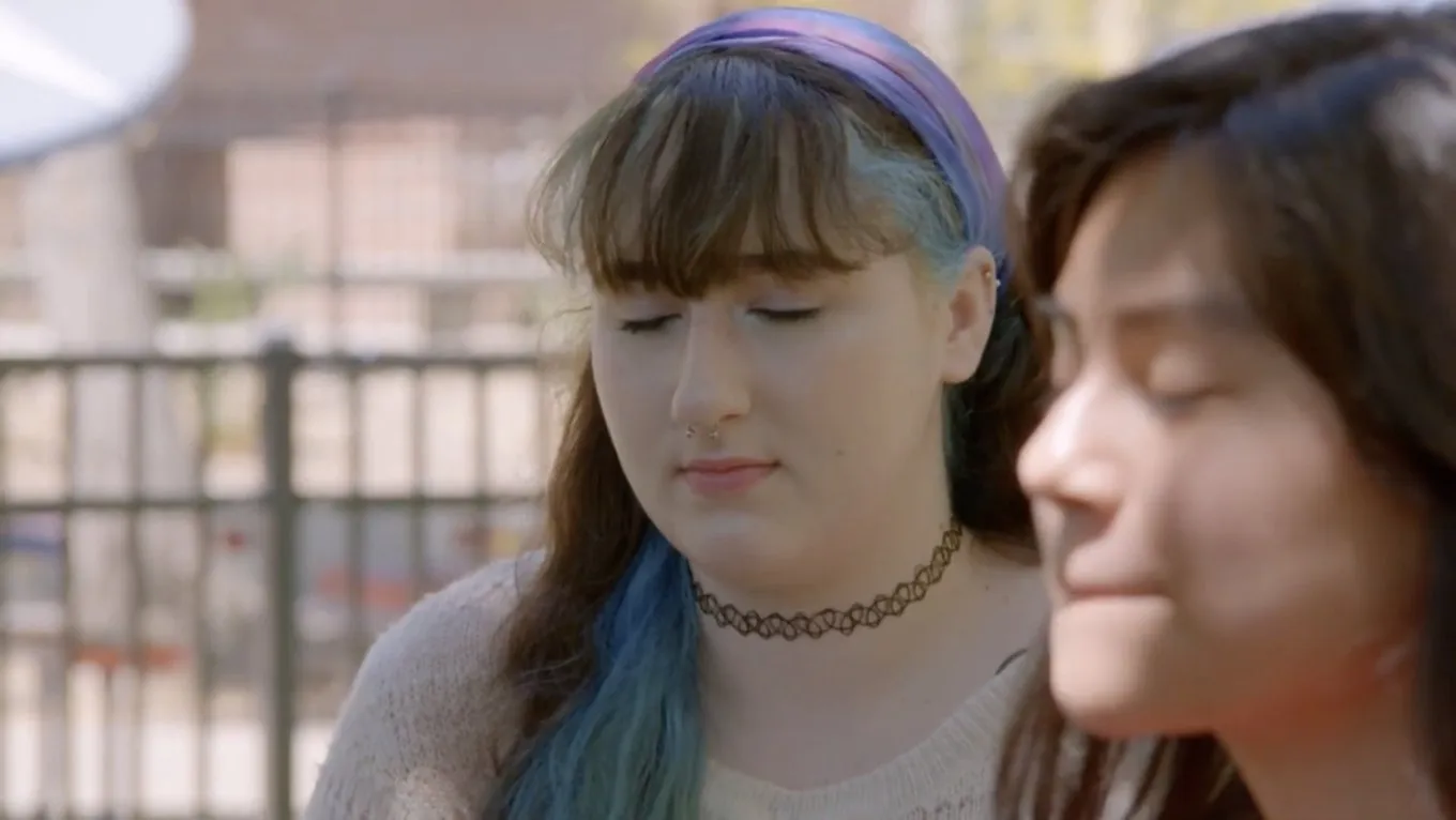 Two high school students sit with their eyes closed during a mindfulness practice
